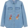 Bring screen-inspired fashion to your wardrobe with the Sadie Soverall Every Year After 2026 Embroidered Denim Snap-Up Shirt. Inspired by the character Percy Fraser, portrayed by Sadie Soverall in the romantic drama series Every Year After, this stylish blue denim shirt captures the relaxed, nature-inspired aesthetic seen throughout the show. Crafted from premium-quality denim, this women's snap-up shirt features eye-catching embroidered mushroom artwork that adds a playful boho touch to a timeless wardrobe staple. The classic shirt collar, dual flap chest pockets, and comfortable relaxed fit make it ideal for layering over tanks, tees, or dresses throughout every season. With embroidered denim continuing to trend in contemporary fashion, this versatile piece blends vintage charm with modern casual style, making it perfect for everyday wear, travel outfits, festivals, and weekend adventures. Whether you're a fan of Every Year After or simply looking for a standout embroidered denim shirt, this Percy Fraser-inspired piece delivers comfort, character, and effortless style.